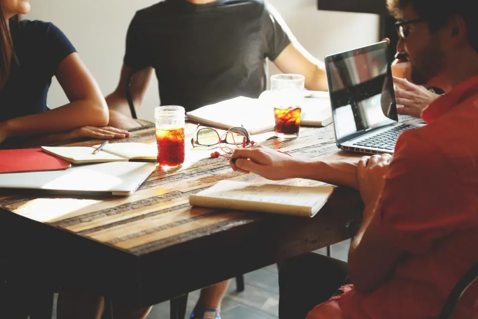 Small team working around a table with notebooks and a laptop