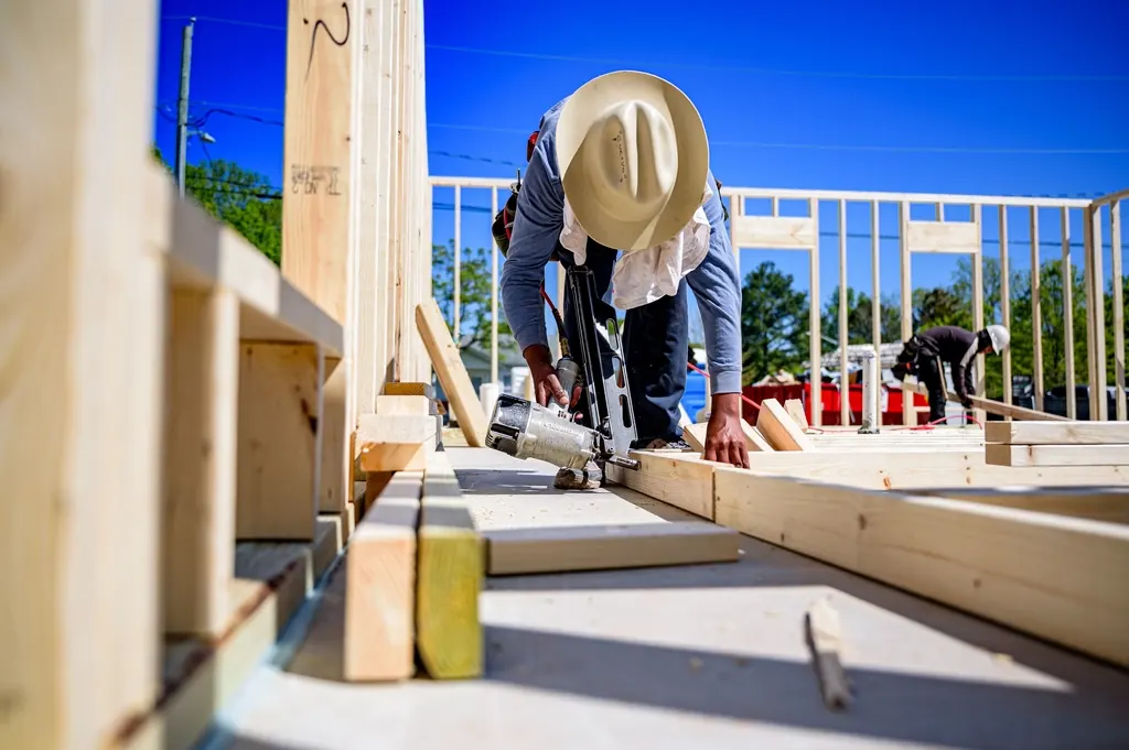 Builder nailing a timber frame together on a job site