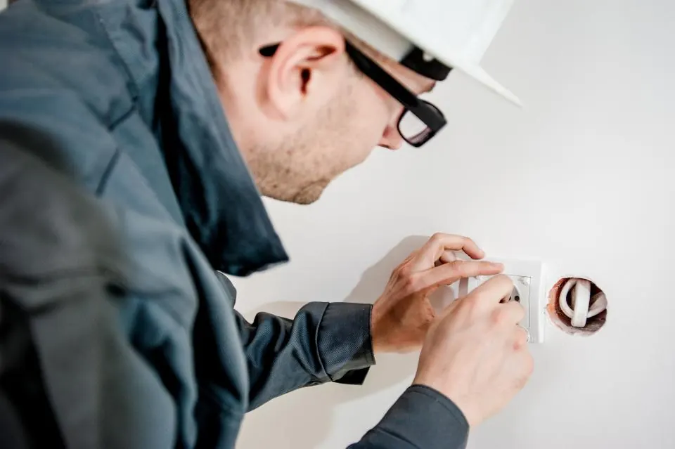 Electrician in a hard hat fitting a wall socket